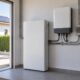 Batería doméstica e inversor en un cuarto técnico con paneles solares visibles al exterior